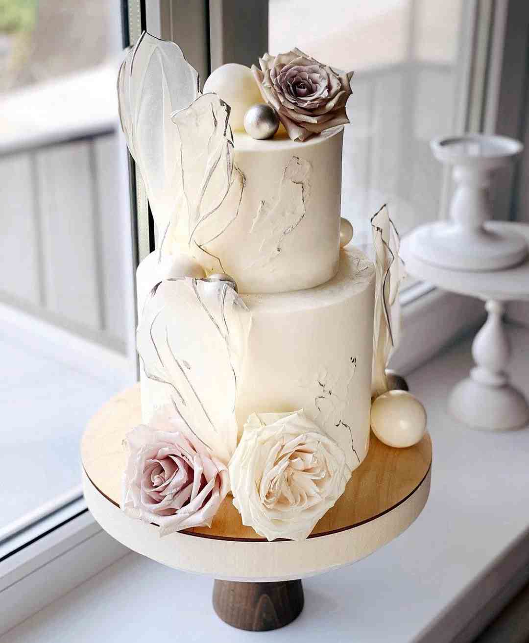 کیک خامه ای دو طبقه سفید با تزئین گل برروی آن